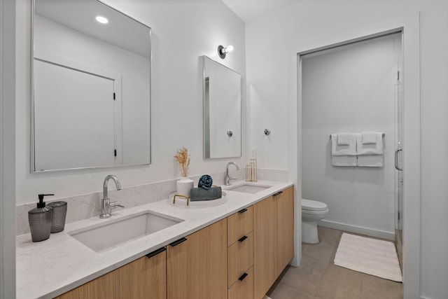 bathroom featuring a shower with shower door, vanity, tile patterned flooring, and toilet