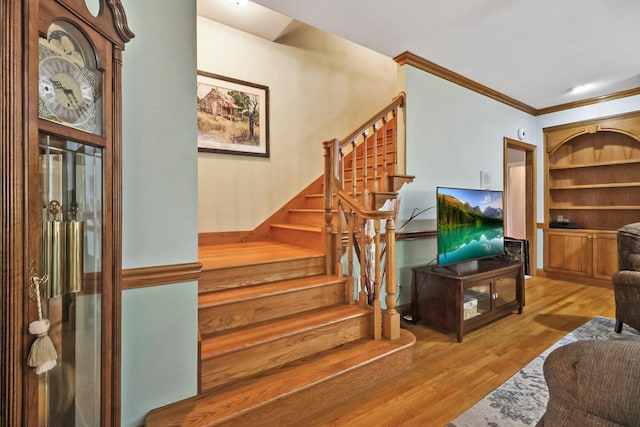 staircase with hardwood / wood-style floors and crown molding