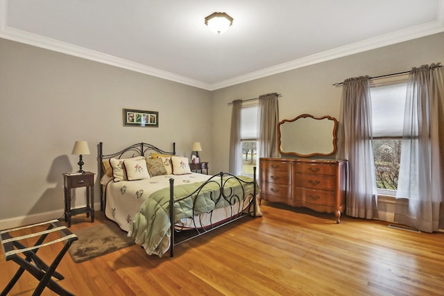 bedroom featuring multiple windows, hardwood / wood-style floors, and crown molding