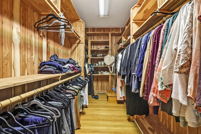 walk in closet with light hardwood / wood-style floors