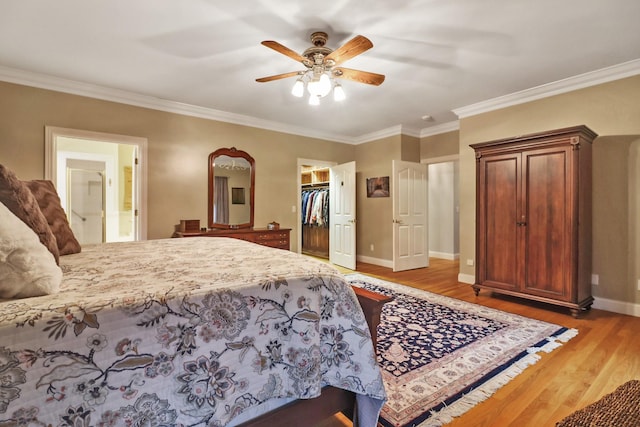 bedroom with ceiling fan, crown molding, a walk in closet, and hardwood / wood-style floors