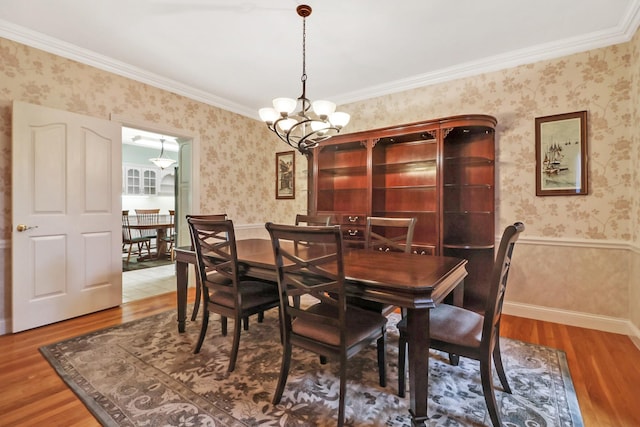 dining area with hardwood / wood-style floors, a notable chandelier, and ornamental molding