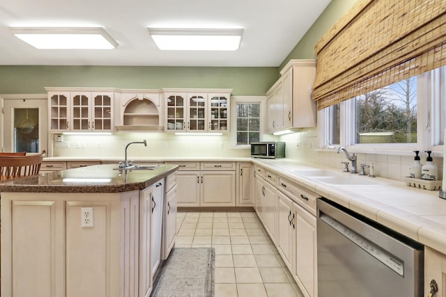 kitchen featuring sink, stainless steel appliances, a kitchen island with sink, and tasteful backsplash