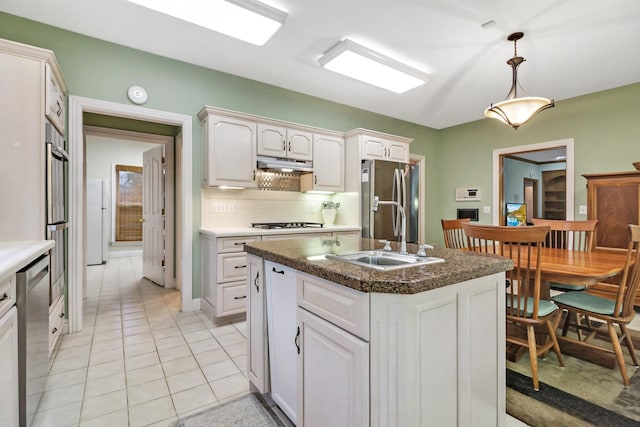 kitchen with a center island with sink, appliances with stainless steel finishes, sink, white cabinetry, and pendant lighting