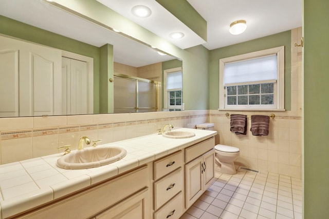 bathroom featuring toilet, tile walls, an enclosed shower, tile patterned floors, and vanity