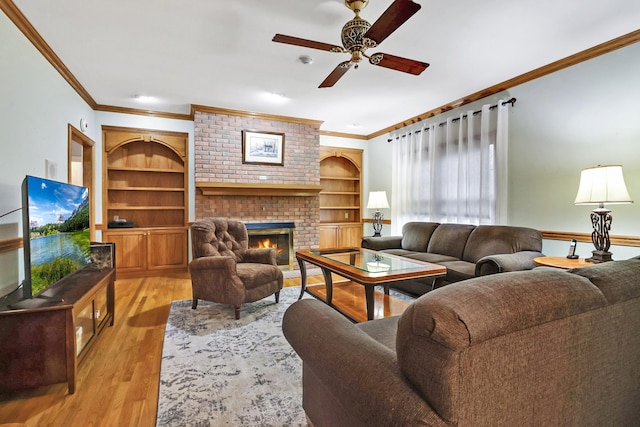 living room with a brick fireplace, light hardwood / wood-style floors, crown molding, and built in features