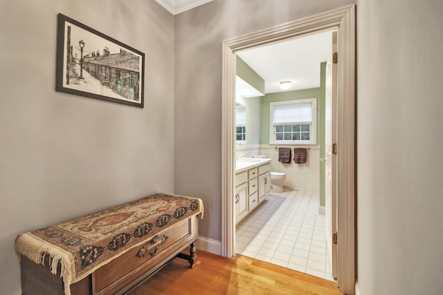 hall with light hardwood / wood-style floors, sink, and tile walls