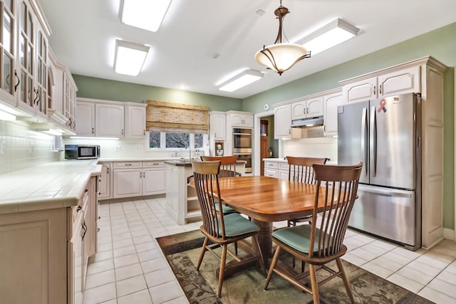 kitchen featuring a center island, stainless steel appliances, light tile patterned floors, decorative backsplash, and pendant lighting