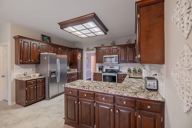 306 Amherst Dr, Tullahoma, TN 37388 - kitchen with stainless steel appliances, a sink, backsplash, a peninsula, and dark brown cabinets