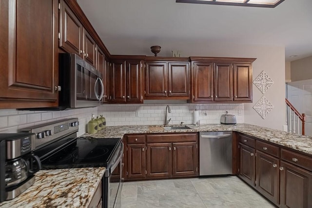 306 Amherst Dr, Tullahoma, TN 37388 - kitchen featuring stainless steel appliances, a sink, backsplash, light stone countertops, and dark brown cabinetry