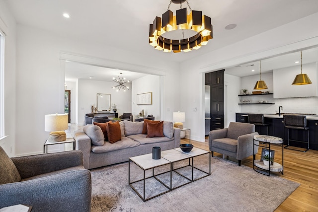 living room with light wood-type flooring, an inviting chandelier, and indoor wet bar