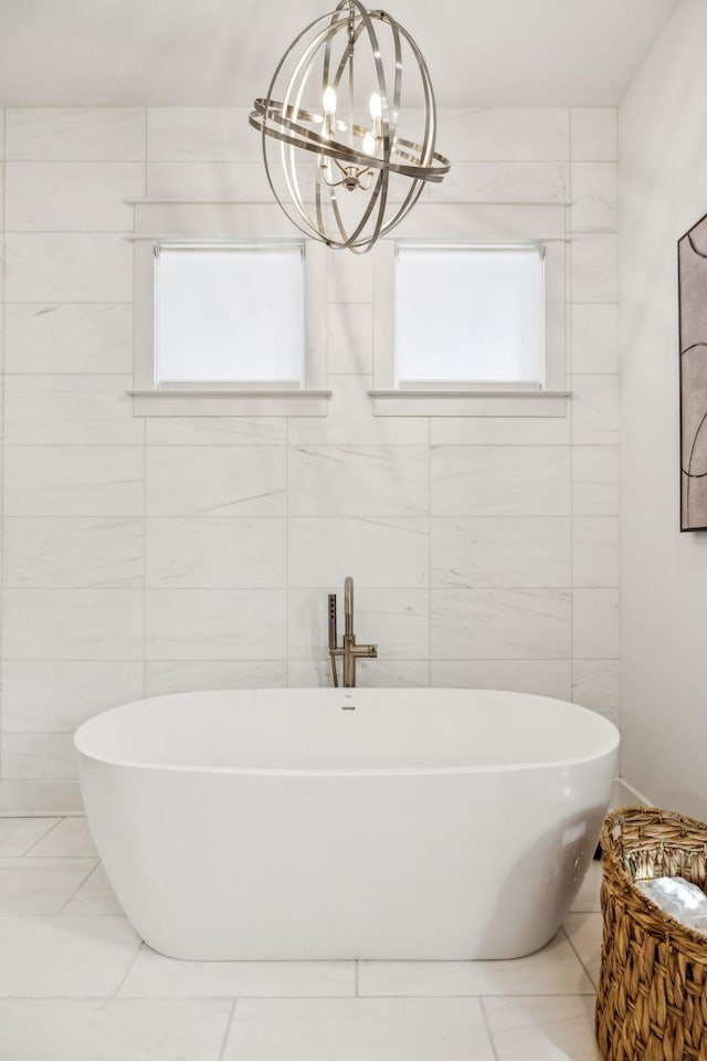 bathroom with an inviting chandelier, tile walls, and a bathing tub