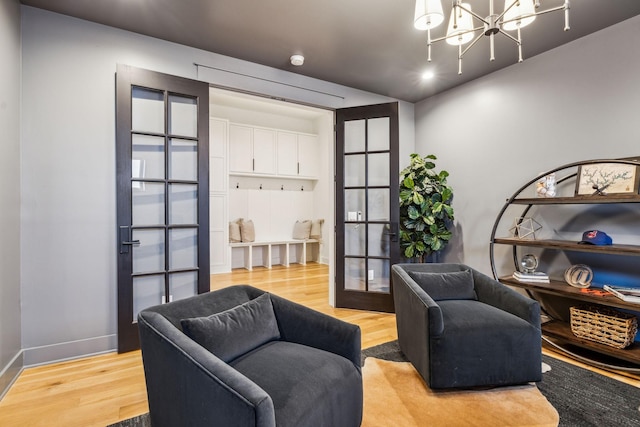 living area featuring french doors, an inviting chandelier, and light hardwood / wood-style floors