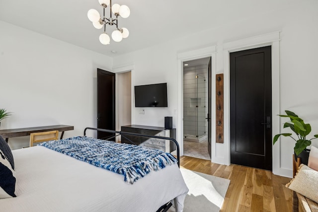 bedroom featuring hardwood / wood-style flooring, connected bathroom, and a notable chandelier