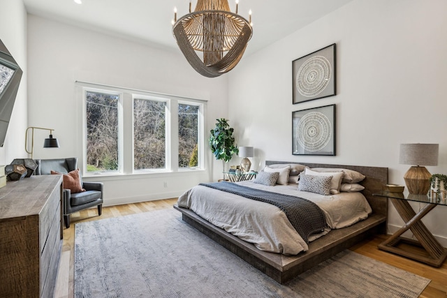 bedroom with light wood-type flooring and an inviting chandelier