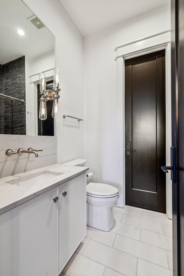 bathroom with toilet, tile patterned flooring, and vanity