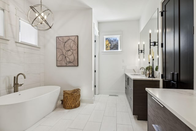 bathroom featuring vanity, a chandelier, and a tub to relax in