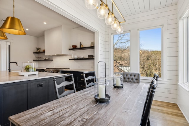 kitchen with pendant lighting, custom exhaust hood, light hardwood / wood-style flooring, and decorative backsplash