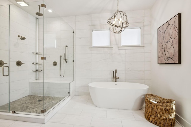 bathroom with an inviting chandelier, separate shower and tub, and tile walls