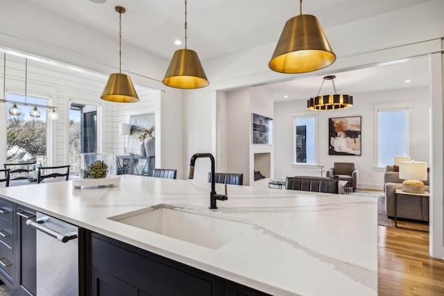 kitchen featuring sink, light stone countertops, light hardwood / wood-style floors, and decorative light fixtures