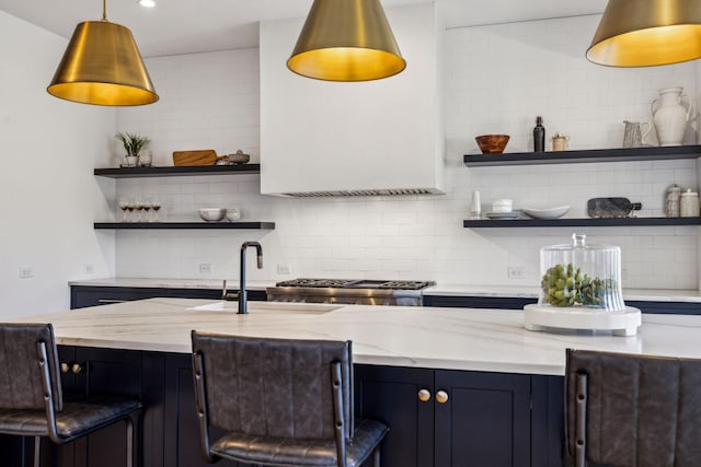 bar featuring range, light stone countertops, decorative light fixtures, backsplash, and sink