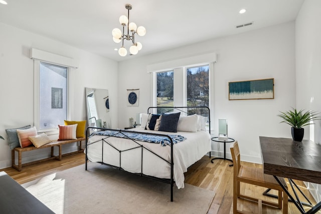 bedroom featuring an inviting chandelier and light hardwood / wood-style floors