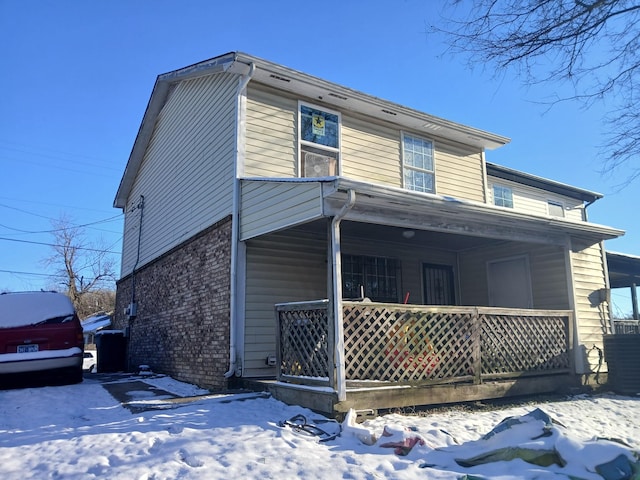 view of front of property featuring a porch, central AC unit, and brick siding