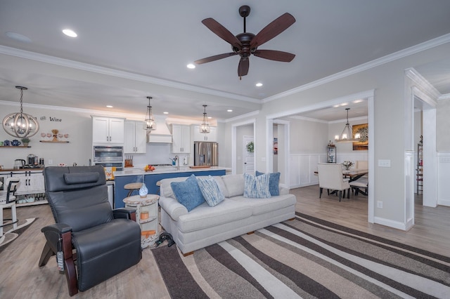 living room with ceiling fan with notable chandelier, sink, light hardwood / wood-style floors, and crown molding