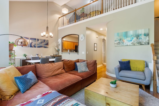 living room featuring a high ceiling, an inviting chandelier, and light hardwood / wood-style floors