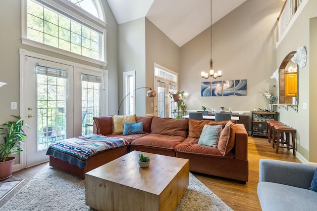 living room featuring high vaulted ceiling, light hardwood / wood-style floors, and an inviting chandelier