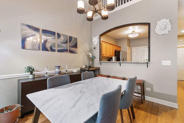 dining area featuring light wood-type flooring and a notable chandelier