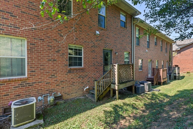 back of house with a lawn, central air condition unit, and a wooden deck