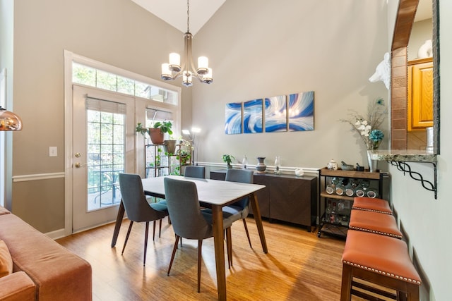 dining room with high vaulted ceiling, a notable chandelier, and light hardwood / wood-style flooring