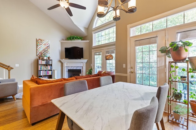 dining room featuring a high end fireplace, high vaulted ceiling, a wealth of natural light, and light hardwood / wood-style flooring