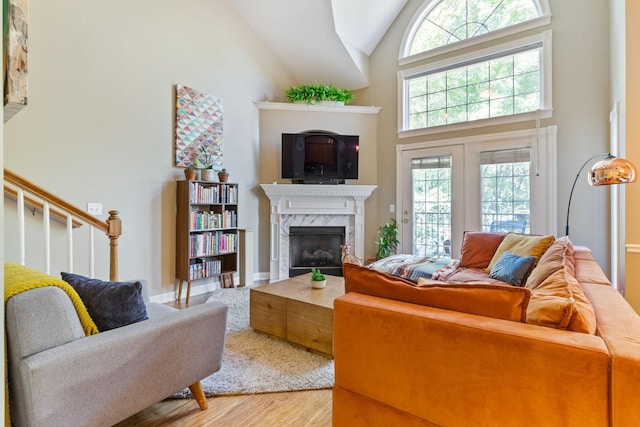 living room with high vaulted ceiling, hardwood / wood-style floors, and a premium fireplace