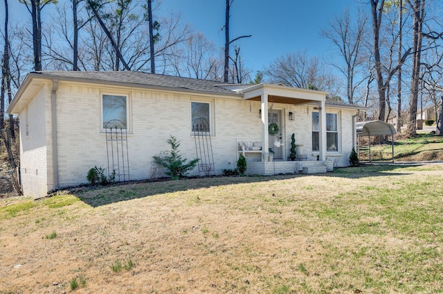 single story home with a detached carport, a porch, a front lawn, and brick siding