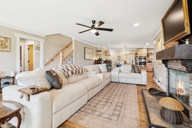 living room featuring ceiling fan with notable chandelier, ornamental molding, and light hardwood / wood-style floors