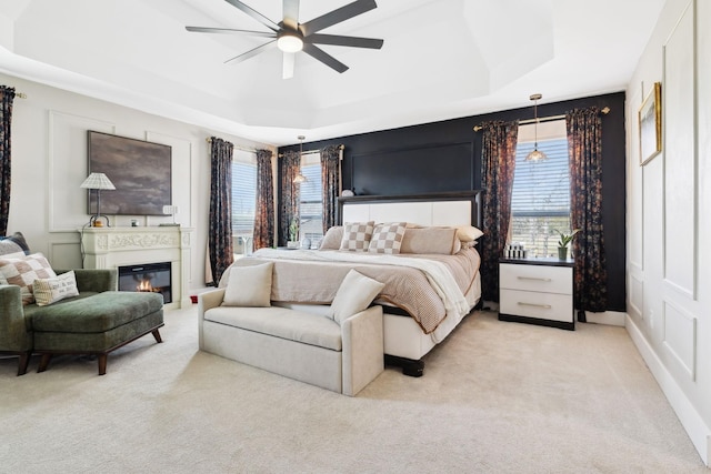 carpeted bedroom featuring a tray ceiling and ceiling fan