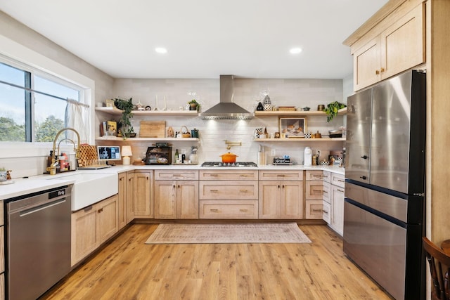 kitchen with sink, wall chimney range hood, light brown cabinets, and stainless steel appliances