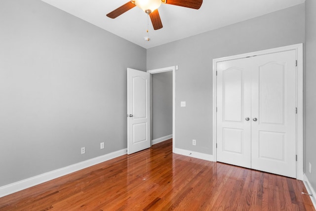 unfurnished bedroom featuring ceiling fan, a closet, and wood-type flooring