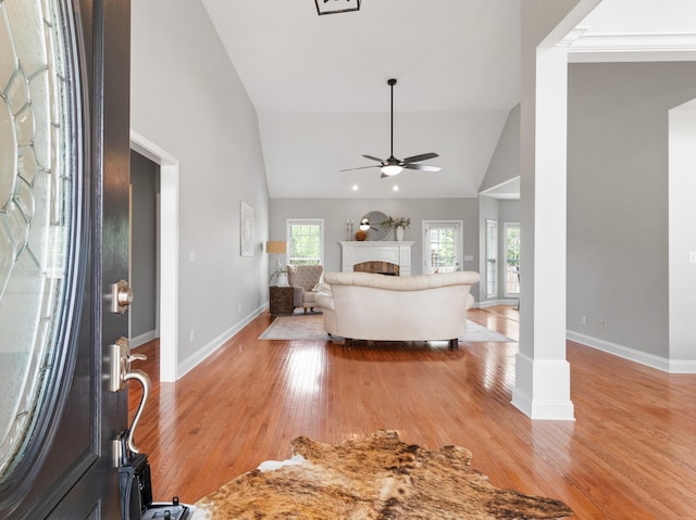 unfurnished living room featuring ceiling fan, high vaulted ceiling, and light wood-type flooring