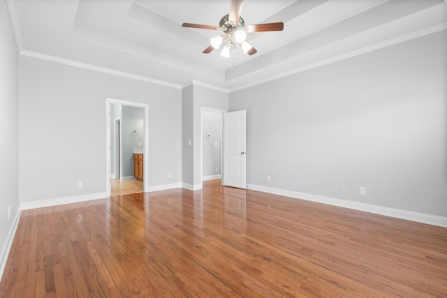 unfurnished bedroom featuring a raised ceiling, light wood-type flooring, ceiling fan, and ornamental molding