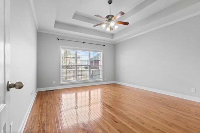 spare room featuring ceiling fan, light hardwood / wood-style flooring, a raised ceiling, and ornamental molding