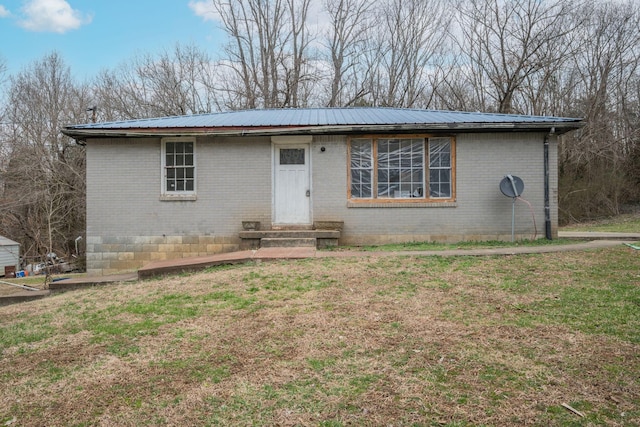 view of front of house with a front yard, brick siding, and metal roof