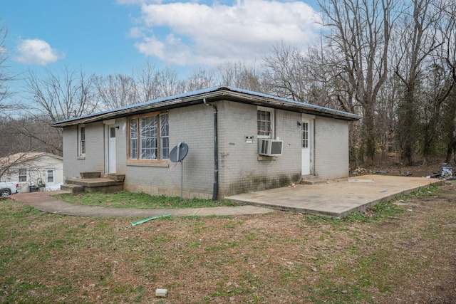 view of side of property featuring cooling unit, brick siding, and a patio