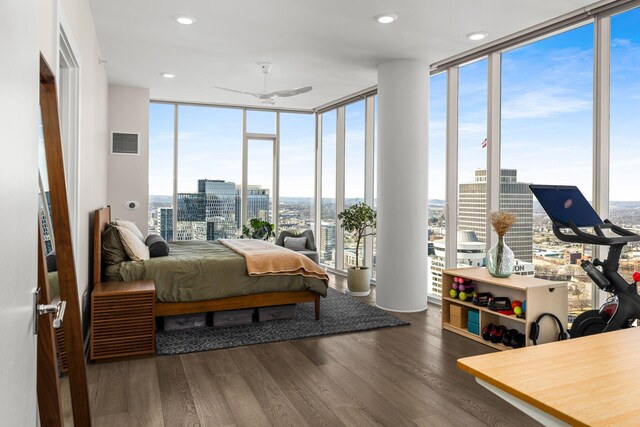 bedroom featuring visible vents, a view of city, a wall of windows, and wood finished floors