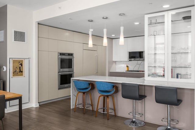 kitchen with visible vents, dark wood-style flooring, stainless steel appliances, a kitchen bar, and modern cabinets