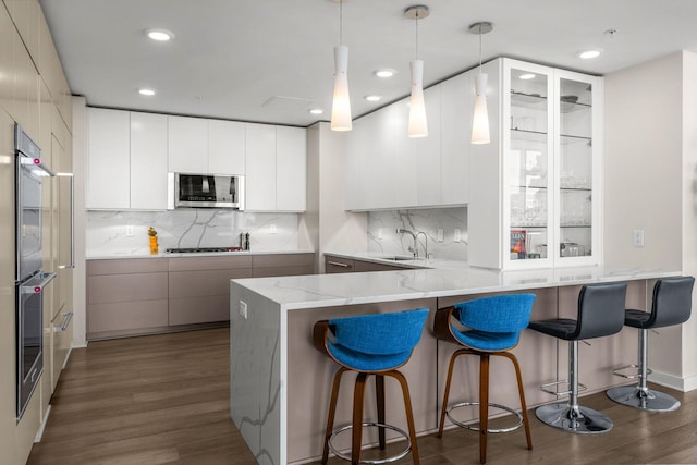 kitchen with a peninsula, modern cabinets, dark wood-style flooring, and appliances with stainless steel finishes