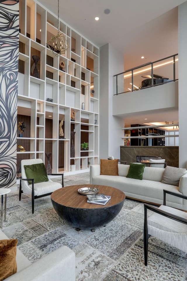 living area featuring a notable chandelier, recessed lighting, a tile fireplace, and a high ceiling
