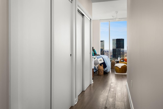 hallway featuring a view of city, baseboards, and hardwood / wood-style flooring
